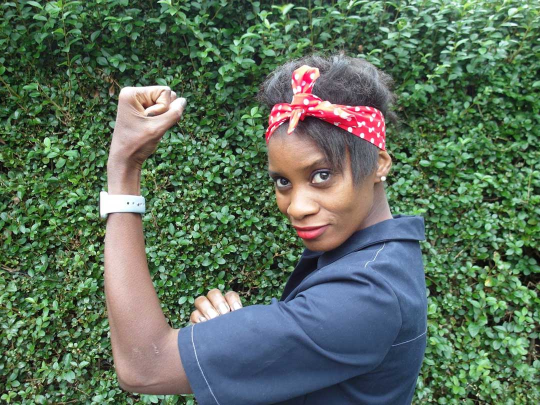 A young black female showing her bicep wearing a red bandana