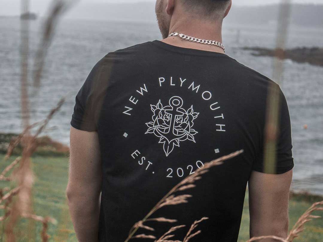 A young male model wearing a New Plymouth t-shirt